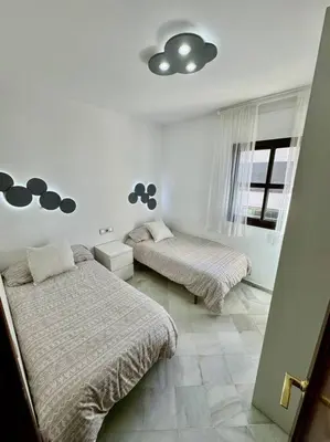 a bedroom with two beds and a window at Piso céntrico y tranquilo con garaje incluido in Sanlúcar de Barrameda