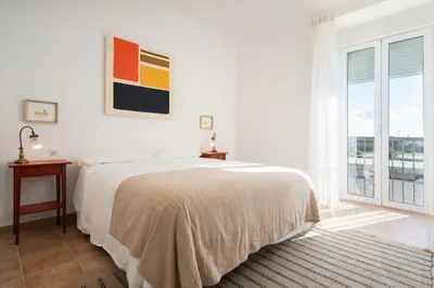 a white bedroom with a bed and a window at Apartoyou - Río Guadalete in El Puerto de Santa María