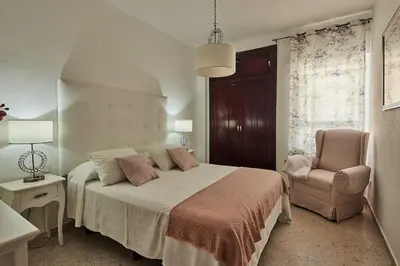 a bedroom with a bed and a chair at Paso del Mar Ha Apartment in Cádiz