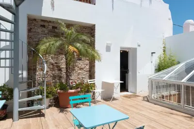 a patio with a blue table and a palm tree at Apartamentos Rosario Centro in Cádiz