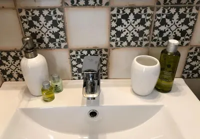 a white sink with three bottles and a cup at Apartamentos Rosario Centro in Cádiz