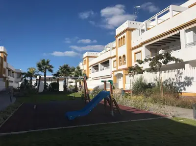 a playground with a slide in front of a building at Dunas de Punta Candor in Rota