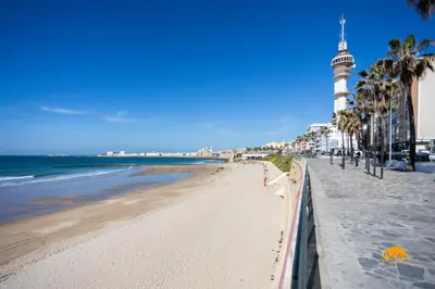 a view of the beach with a lighthouse in the distance at Balcón de Santa María Free Parking by Cádiz Time in Cádiz
