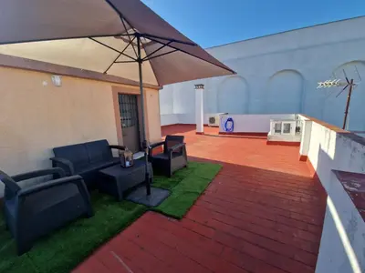 a patio with chairs and an umbrella and grass at Casa Consuelo in Jerez de la Frontera