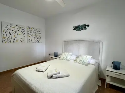 a bedroom with a large white bed with towels on it at Los Porches in Chiclana de la Frontera