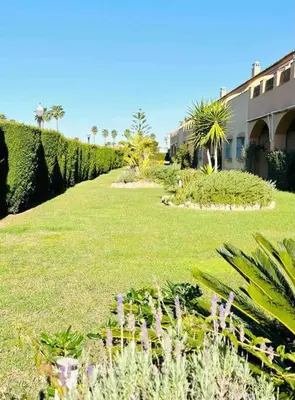 a lawn with flowers and plants in a yard at Adosado en Novo Atlantico Golf in Novo Sancti Petri