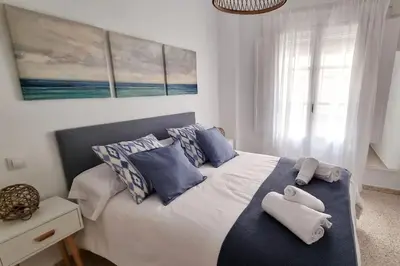 a bedroom with a bed with blue and white pillows at Casa Quili Cádiz com in Cádiz