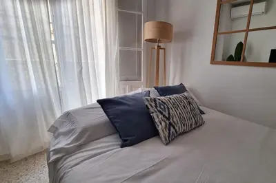 a bed with two blue pillows in a room with a window at Casa Quili Cádiz com in Cádiz