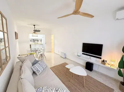 a white living room with a couch and a flat screen tv at Casa Quili Cádiz com in Cádiz
