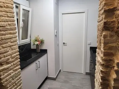 a kitchen with white cabinets and a mirror and a door at Apartamento Demasiadas Compañías in Cádiz