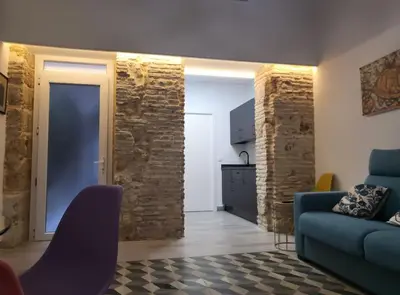 a living room with a blue couch and a kitchen at Apartamento Demasiadas Compañías in Cádiz