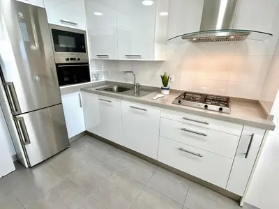 a kitchen with white cabinets and a stainless steel refrigerator at GATU Arena 