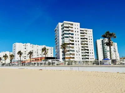 a beach with two tall buildings and palm trees at GATU Arena 
