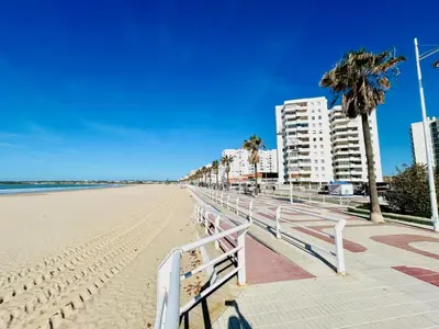 a sandy beach with palm trees and buildings at GATU Arena 