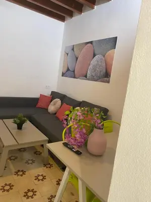 a living room with a couch and a table with flowers at SOTAVENTO La Solera in Sanlúcar de Barrameda