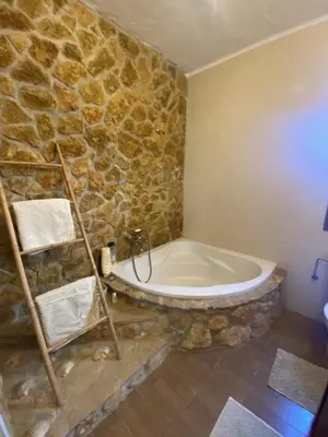 a bathroom with a stone wall and a bath tub at House near Conil with a Tropical Garden and Pool in Conil de la Frontera
