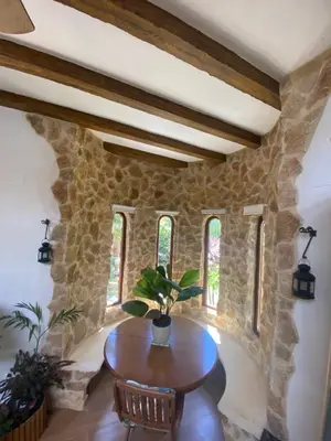 a dining room with a wooden table and a stone wall at House near Conil with a Tropical Garden and Pool in Conil de la Frontera