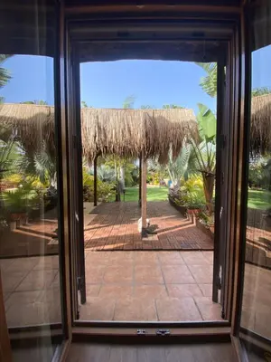 an open door to a patio with a thatch roof at House near Conil with a Tropical Garden and Pool in Conil de la Frontera