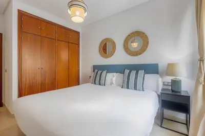 a bedroom with a white bed and a wooden cabinet at Moon Dreams Puerto in El Puerto de Santa María