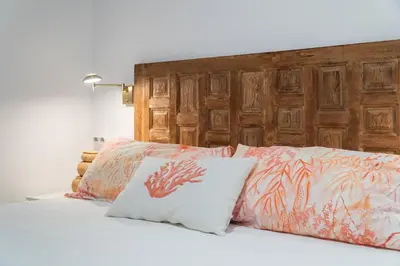 a bed with a wooden headboard and two pillows at Apartoyou - Ruiseñor Puerto in El Puerto de Santa María