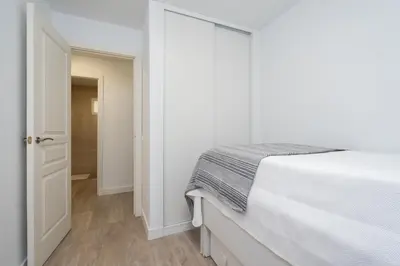 a white bedroom with a bed and an open door at Apartoyou - Ruiseñor Puerto in El Puerto de Santa María