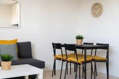 a dining room table with two chairs and a clock at Apartoyou - Estudio del Sol in El Puerto de Santa María