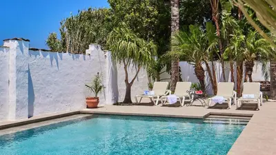 a swimming pool with chairs and a table and trees at Casa García Camacho Conil de la Frontera by Ruralidays in Conil de la Frontera