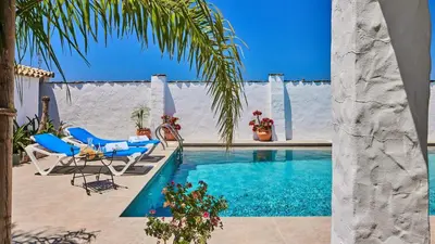 a swimming pool with two chairs and a table at Casa García Camacho Conil de la Frontera by Ruralidays in Conil de la Frontera