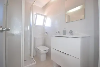 a white bathroom with a toilet and a sink at Casas Buenavista in Conil de la Frontera