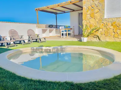 a pool in a yard with chairs and a patio at Casas Buenavista in Conil de la Frontera
