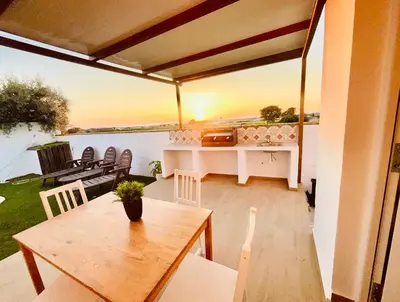 a patio with a table and chairs and the sunset at Casas Buenavista in Conil de la Frontera