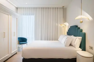 a bedroom with a large bed and a blue chair at Tandem Solera in Jerez de la Frontera