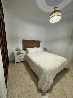 a white bedroom with a bed and a night stand at Bonito y ubicación inmejorable in Sanlúcar de Barrameda
