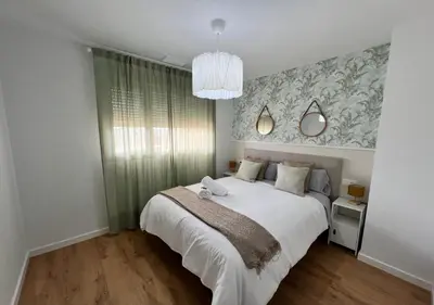 a bedroom with a large white bed and a chandelier at Jardines del Porvenir 2 in Puerto Real