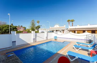 a swimming pool with two lounge chairs and a house at Apartamento Casa Postas III in Conil de la Frontera