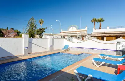 a swimming pool with two lounge chairs and a house at Apartamento Casa Postas IV in Conil de la Frontera