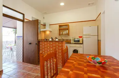 a kitchen with a wooden table and a white refrigerator at Apartamento Casa Postas IV in Conil de la Frontera