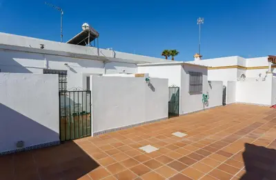 a white building with a gate and a tile courtyard at Apartamento Casa Postas I in Conil de la Frontera