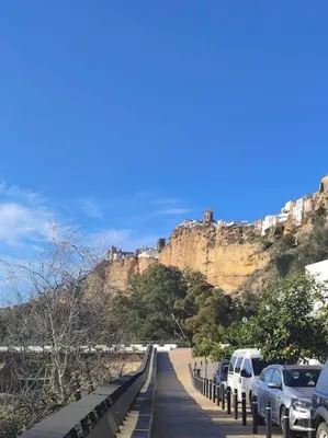 a road with cars parked on the side of a mountain at Casa Mirador del Puente in Arcos de la Frontera