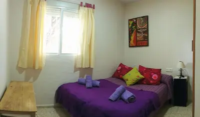 a bedroom with two beds with purple sheets and pillows at Casa de campo con piscina in Chiclana de la Frontera