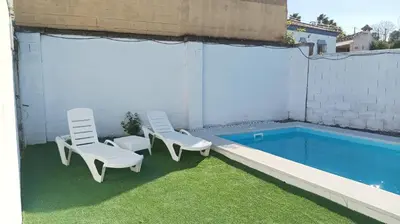 two chairs and a swimming pool on the side of a building at Casa de campo con piscina in Chiclana de la Frontera