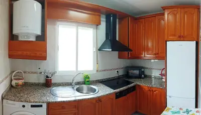 a kitchen with wooden cabinets and a sink and a window at Casa de campo con piscina in Chiclana de la Frontera