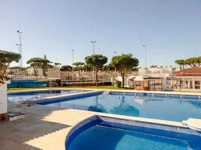 a large blue swimming pool with trees in the background at Las Torres 197 in Novo Sancti Petri