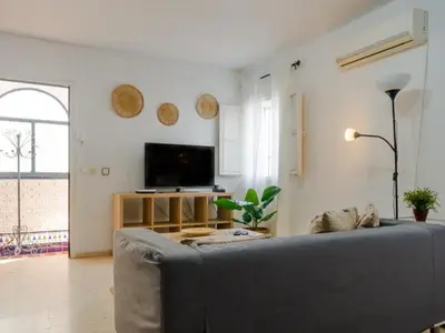 a living room with a couch and a flat screen tv at Las Torres 197 in Novo Sancti Petri