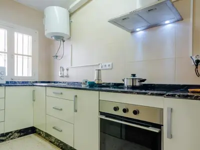a kitchen with white cabinets and a stove top oven at Las Torres 197 in Novo Sancti Petri