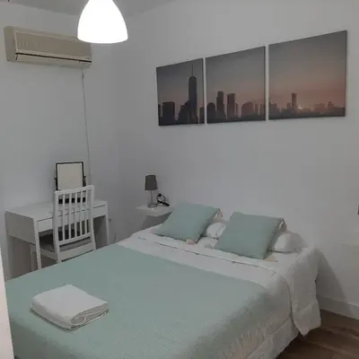 a white bedroom with a bed and a desk at Piso cercano al recinto ferial in Jerez de la Frontera