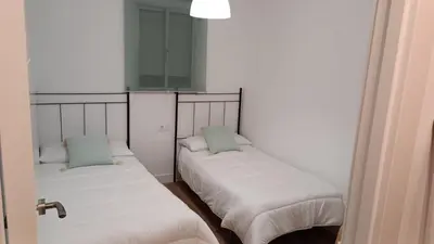 a room with two beds with white sheets and blue pillows at Piso cercano al recinto ferial in Jerez de la Frontera