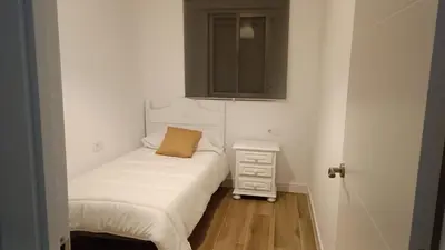 a small bedroom with a bed and a dresser at Piso cercano al recinto ferial in Jerez de la Frontera