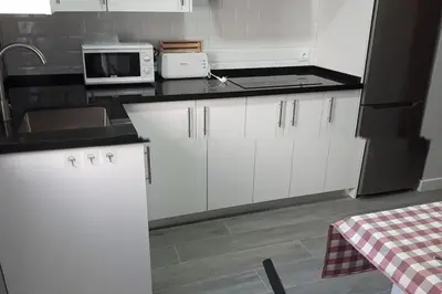 a kitchen with white cabinets and a black microwave at Sanlucar-Centro in Sanlúcar de Barrameda