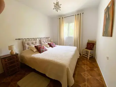 a bedroom with a white bed and a chair at Casa Isabela in Chiclana de la Frontera